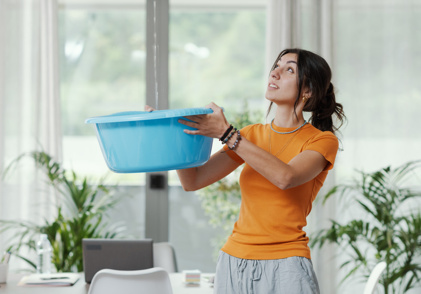 Woman collecting water leaking from the ceiling